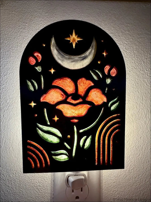 A glowing black night light with elegant flowers, crescent moon, and stars in metallic gold and green accents