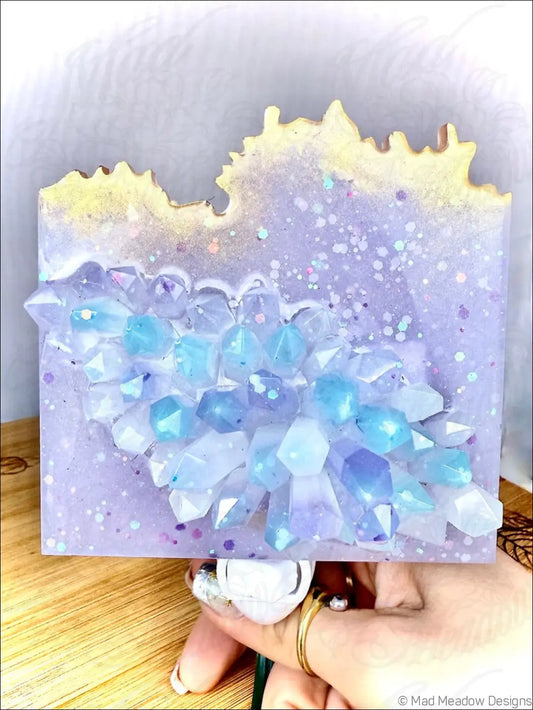 A glowing crystal cluster wall night light with lavender resin canvas and blue white translucent crystals on plug-in base