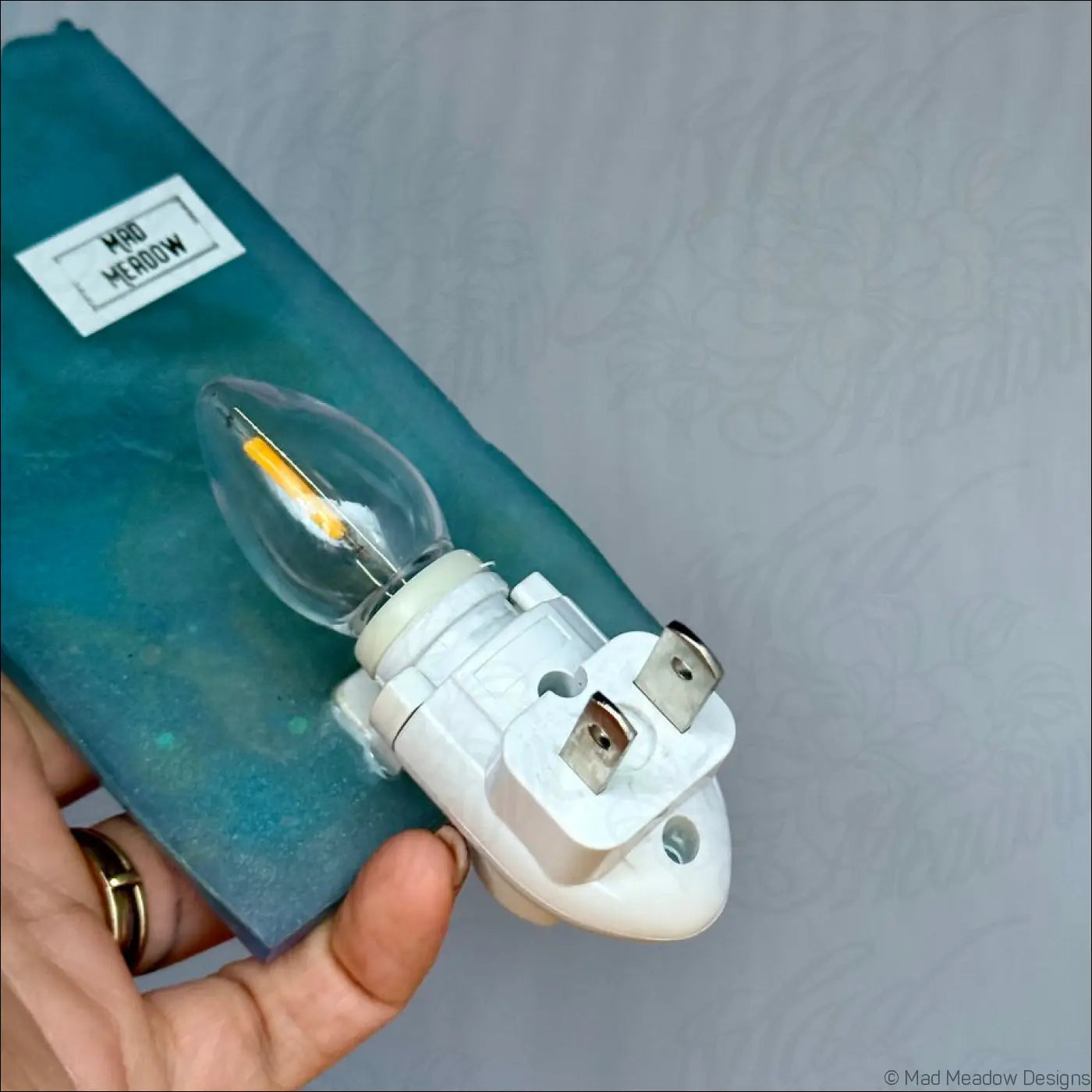 A clear glass led bulb with white plug base and metal prongs for the mesmerizing magician tarot resin wall light
