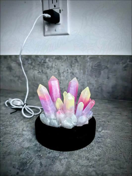 Large resin crystal cluster glow in the dark lamp with pink and yellow resin crystals on a black wooden base
