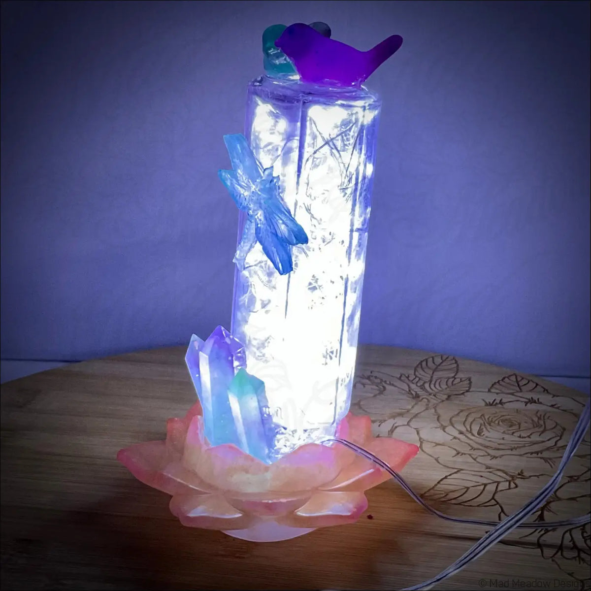 A glowing antique amethyst glass apothecary bottle usb light with fairy lights and butterfly accents on pink lotus base