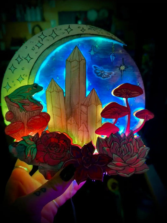 A glowing circular led light box featuring an intricately hand-painted laser mushroom forest ablaze with crystal spires and a green frog