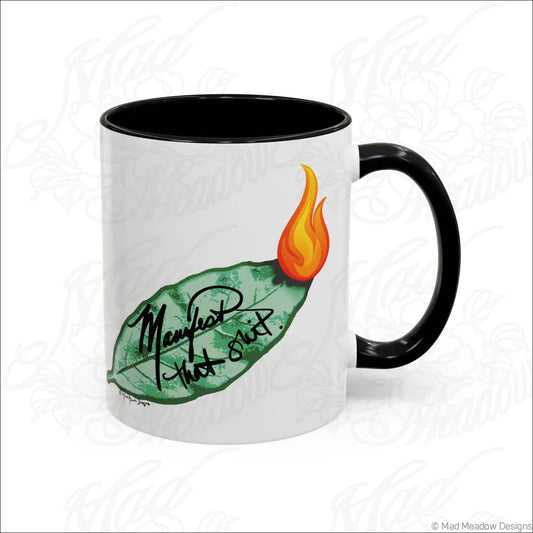 White ceramic mug with glossy finish black handle and interior featuring colored bay leaf and flame design manifest that shit text