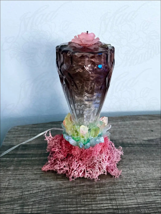 A translucent purple glass usb light candle holder with pink rose and quartz crystal points on pink moss base