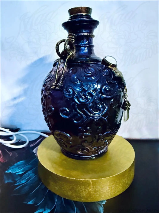Deep blue glass potion bottle light with intricate carvings metallic accents and cork stopper with crystal dangles