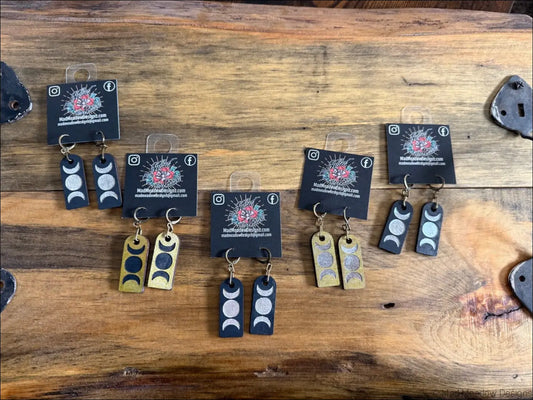 Black and gold triple moon wooden earrings with minimalist engraved lunar phases on rectangular metal tags
