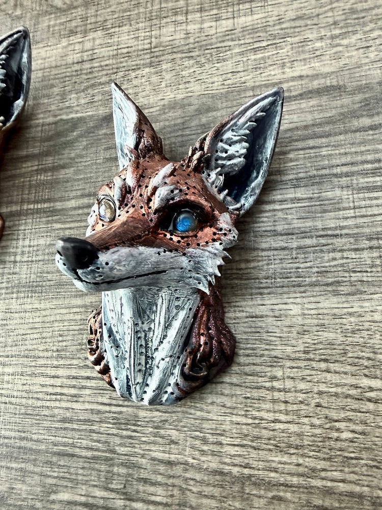 A detailed three-dimensional fox head brooch with metallic finish and vibrant blue eye from art and sculptural collection