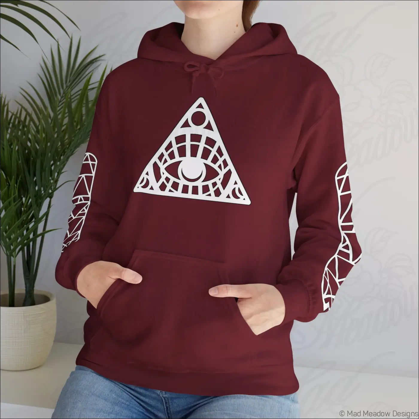 Maroon all-seeing eye triangle hoodie with white geometric eye design, kangaroo pouch, patterned sleeves, tumble dry care instructions
