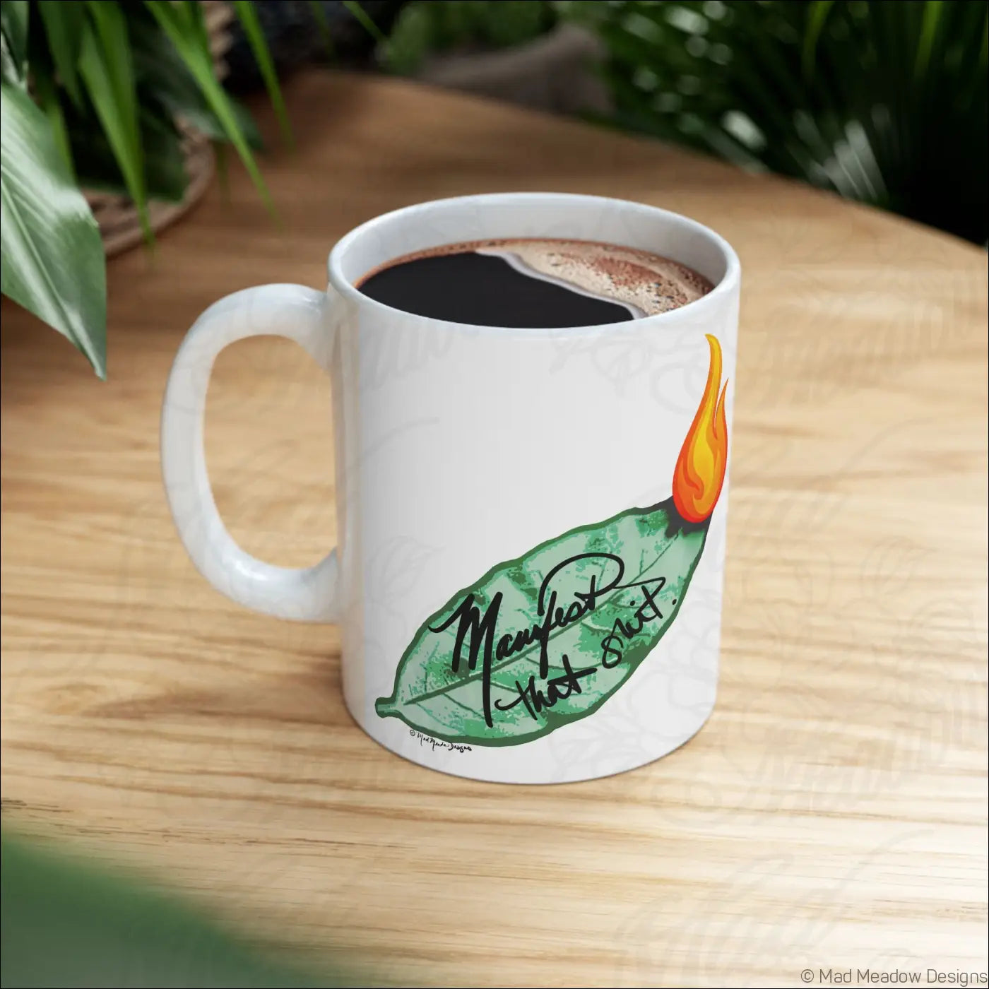 Glossy white ceramic mug with comfortable c-handle featuring hand-drawn green leaf and orange flame design with mewhat that shit text