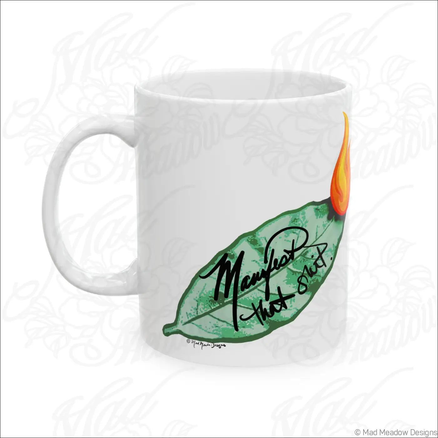 Glossy white ceramic mug with hand-drawn green leaf and orange flame design and comfortable c-handle says manifest that stuff