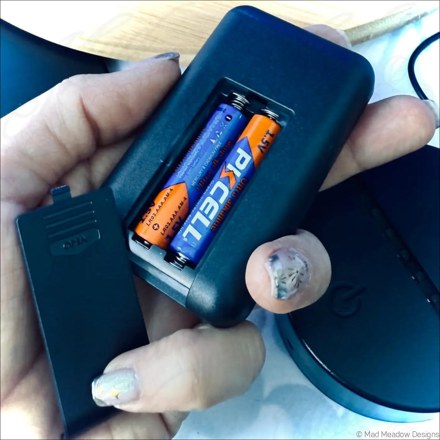 Black plastic battery charger holding two pkcell aa batteries for chakra night light with glowing crescent moon and rainbow disks