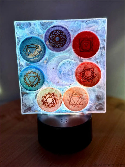 A square translucent resin chakra night light with rainbow-colored disks and a glowing crescent moon design