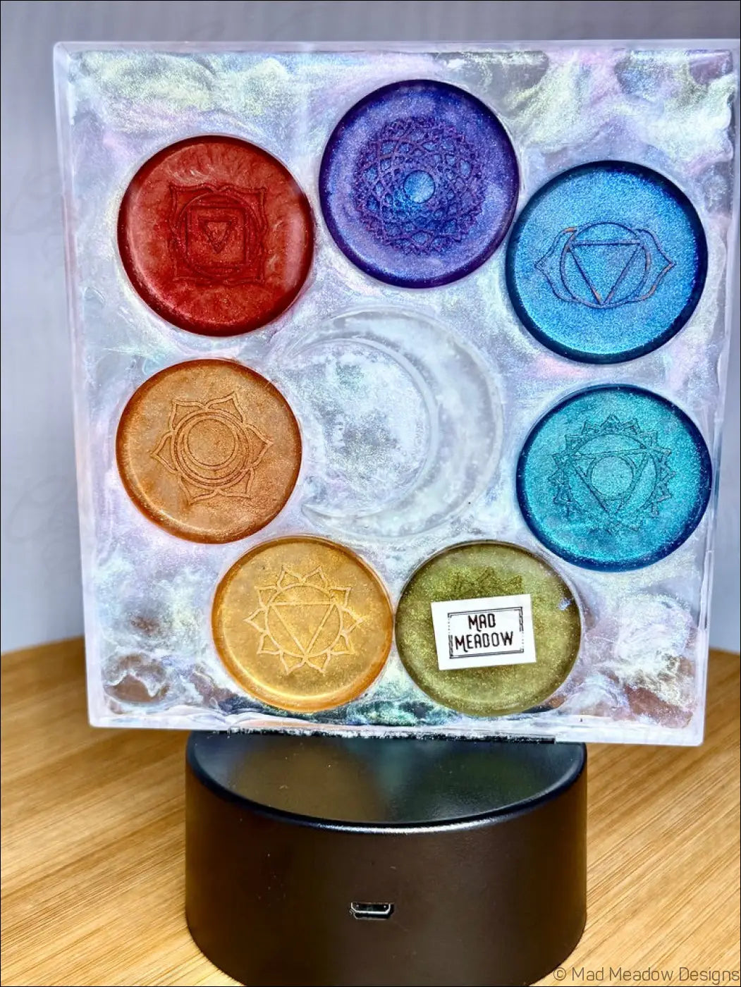 A square resin chakra night light with rainbow-colored disks arranged in a swirling white and silver base with a glowing crescent moon