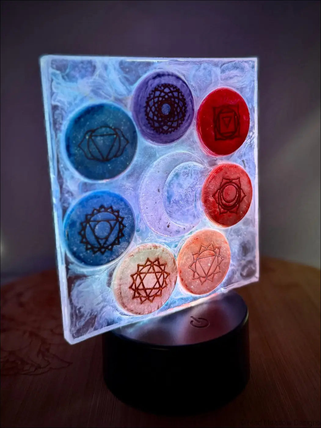 A translucent chakra night light with frosted glass featuring rainbow-colored disks and a glowing crescent moon design