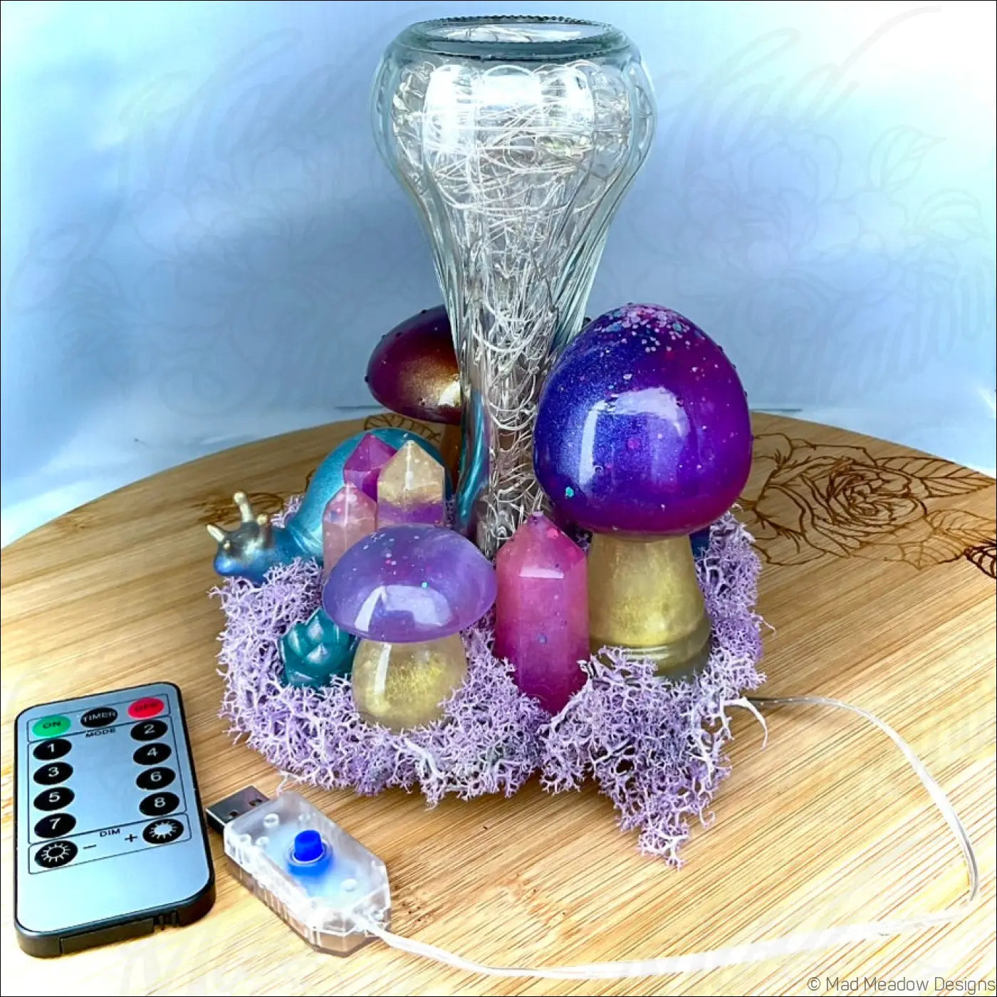 Purple and gold handcrafted resin mushrooms with glittery caps and snail companion sit in lavender moss by a USB powered tabletop light