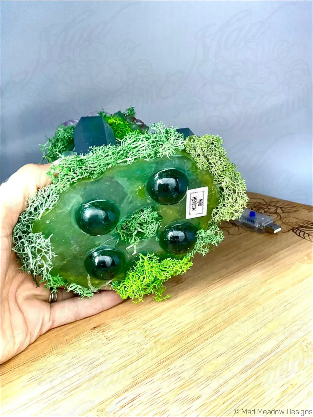 A translucent green resin crystal filled garden light with dark green beads and moss on a vintage glass bottle usb powered