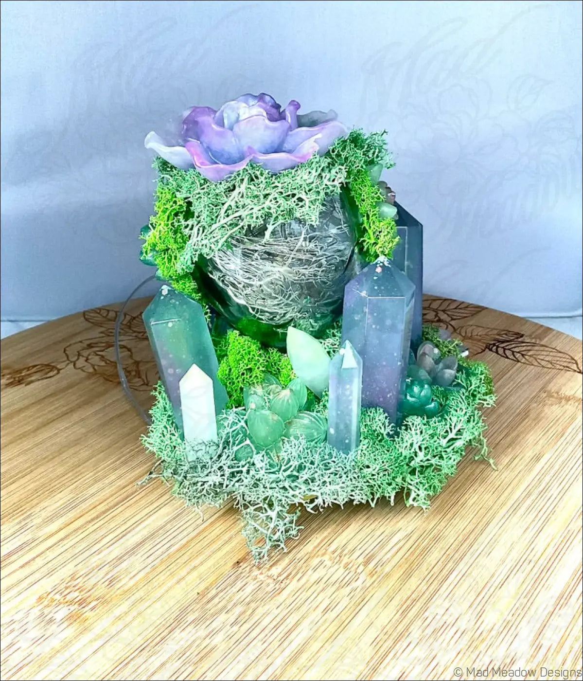 A usb powered vintage glass bottle with a purple and green crystal garden centerpiece featuring moss and succulents