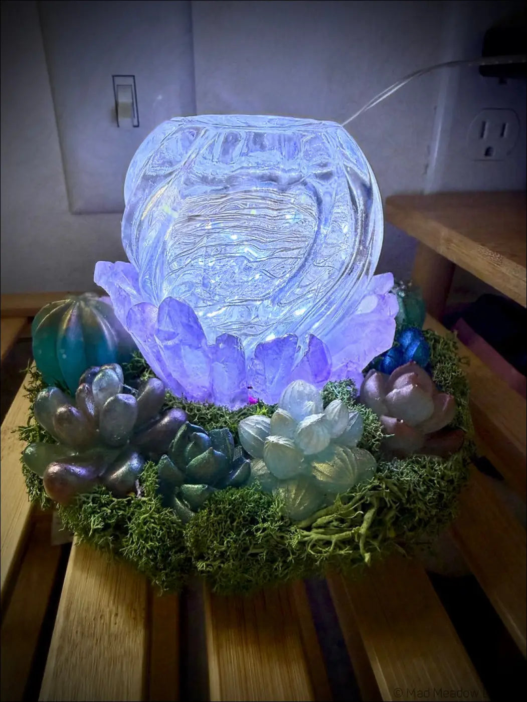 A glowing glass orb with etched patterns sits on colorful succulents and moss in a usb powered garden light