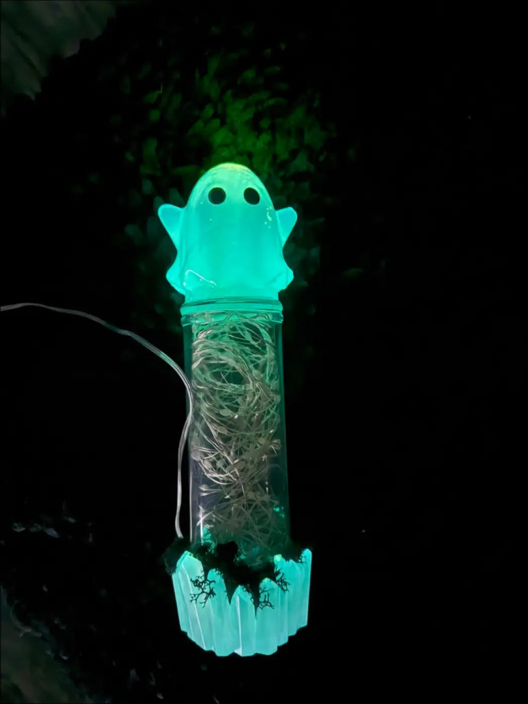 A cute glowing teal ghost usb light with clear body, moss, tangled wire, and a translucent plastic cap
