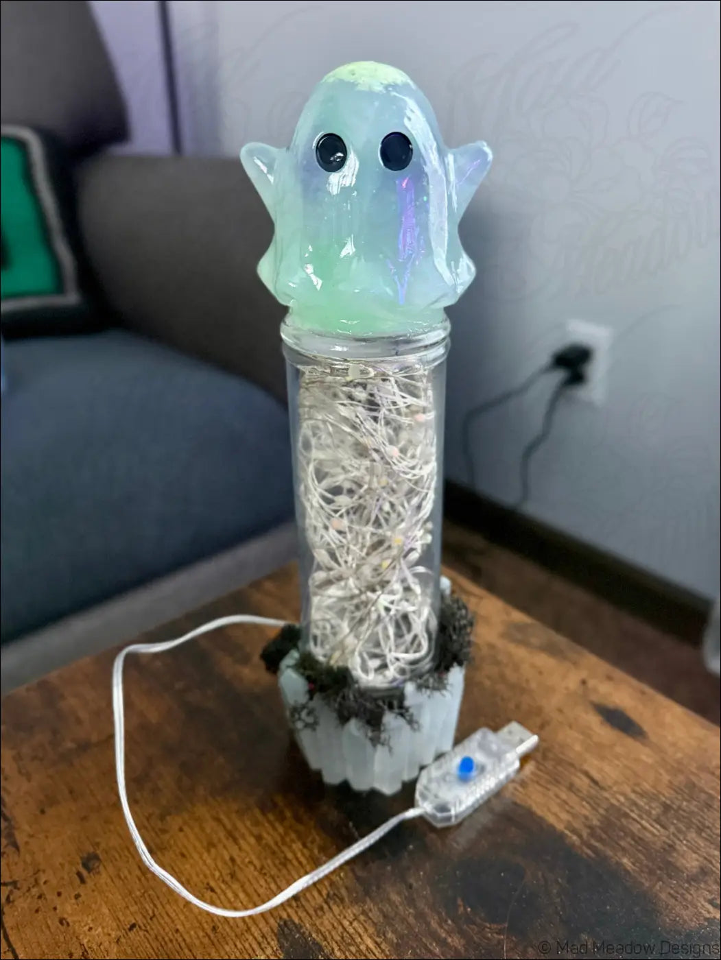Cute glowing green ghost usb light with translucent design sits on glass cylinder filled with moss and white wires