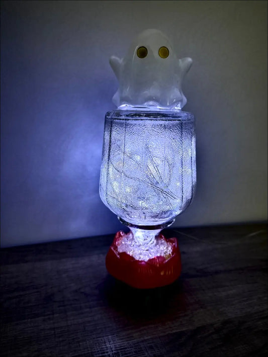 A vintage glass bottle usb fairy lights lantern with a glowing ghost figurine and frosted textured surface