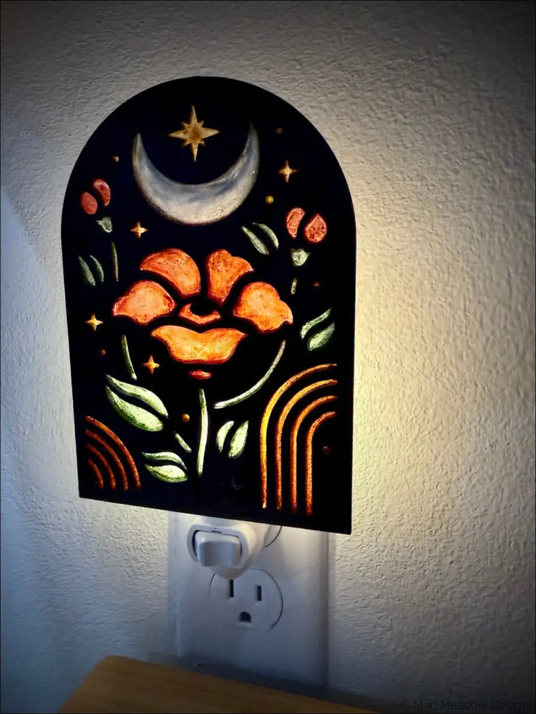 A black arched night light with elegant flowers glowing orange flower moon star and rainbow design