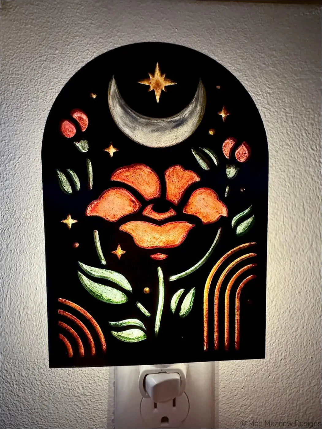 A glowing black night light with elegant flowers, crescent moon, and stars in metallic gold and green accents