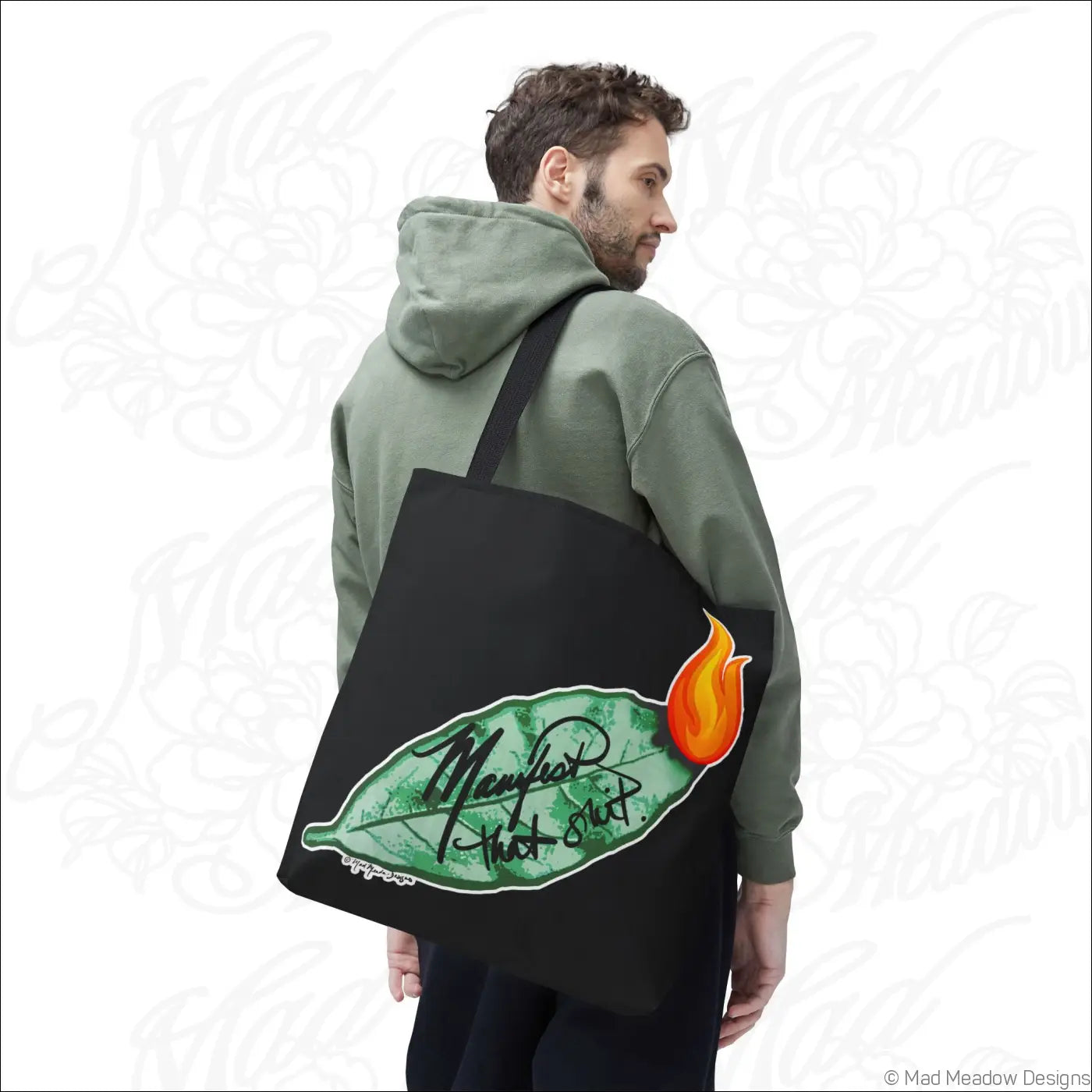 Black canvas flaming bay leaf tote bag with boxed corners featuring manifest that shit cursive and orange flame graphic care instructions included