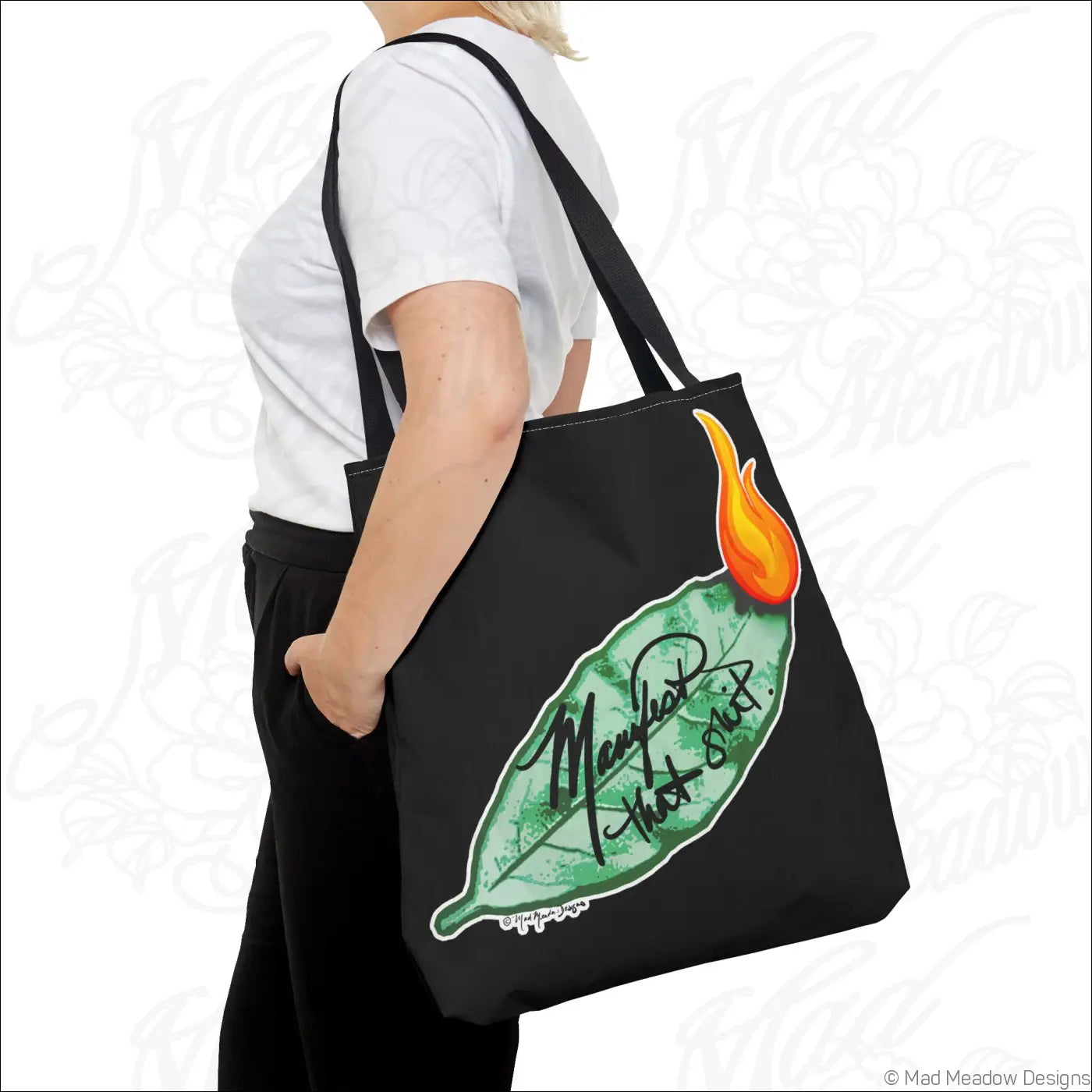 Black canvas flaming bay leaf tote bag with orange flame, cursive manifest that text, boxed corners, non-woven laminate