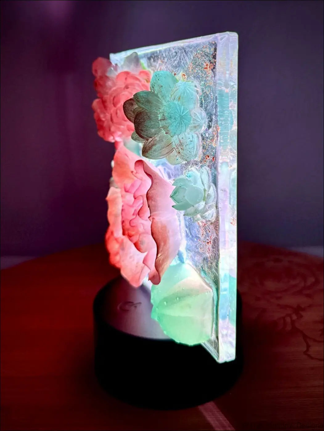 A translucent resin pastel garden nightlight with pink and teal floral sculptures glowing in dreamy hues
