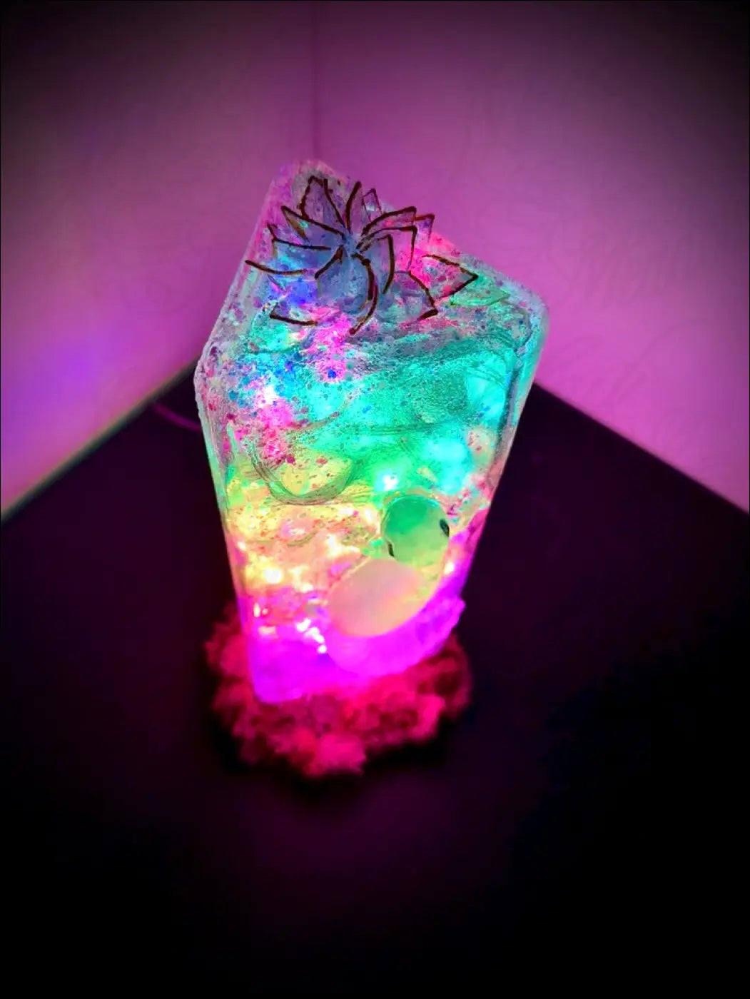 A glowing translucent resin usb lamp with colorful glitter and a black wire spider on top from gecko and lotus