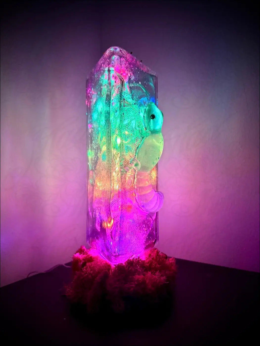A glowing translucent resin usb lamp with colorful lights and a whimsical gecko and lotus sea creature inside