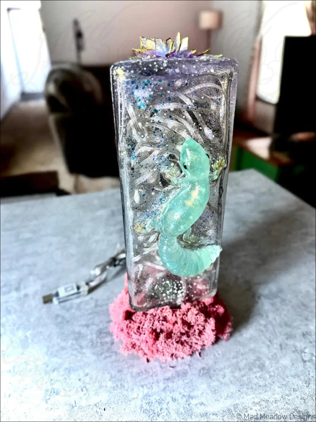 A translucent resin gecko keepsake with glowing teal figure silver glitter and gold leaf for gecko and lotus usb light