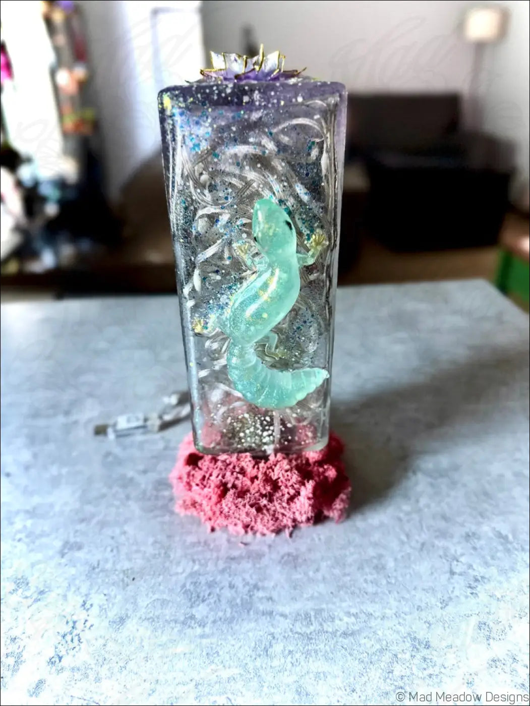 A gecko and lotus glass bottle usb light with translucent resin keepsake featuring a glowing turquoise salamander and purple lotus
