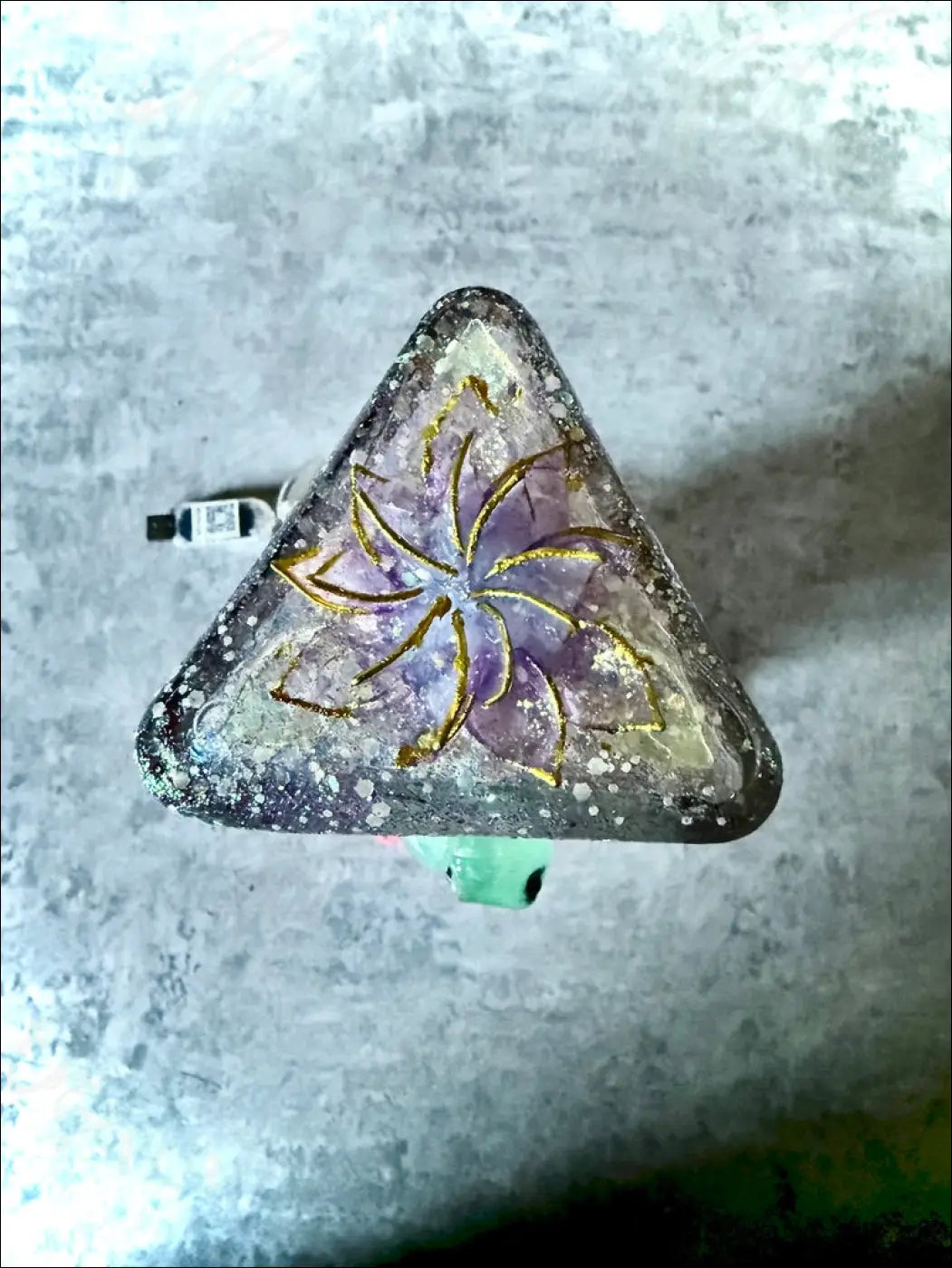 A triangular resin pendant with purple amethyst stone gold leaf floral design and glitter on gecko and lotus usb light