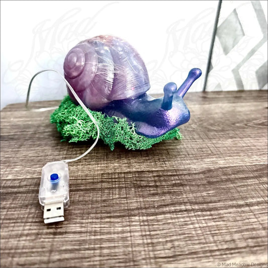 Giant pastel blue and purple snail usb with iridescent translucent shell and blue body resting on green moss base