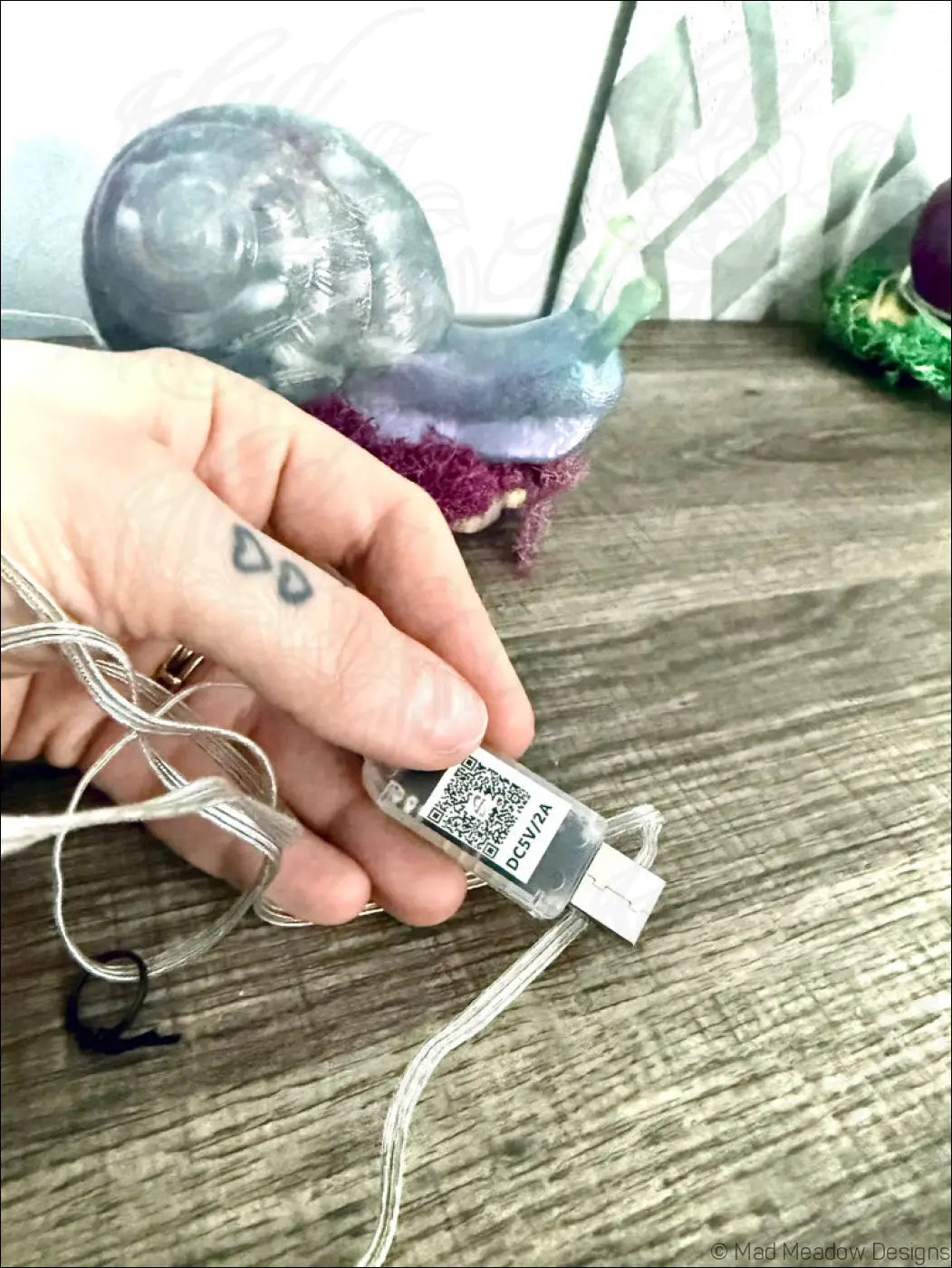 Clear plastic usb flash drive with qr code connected to silver string lights for giant pastel blue and purple snail usb light