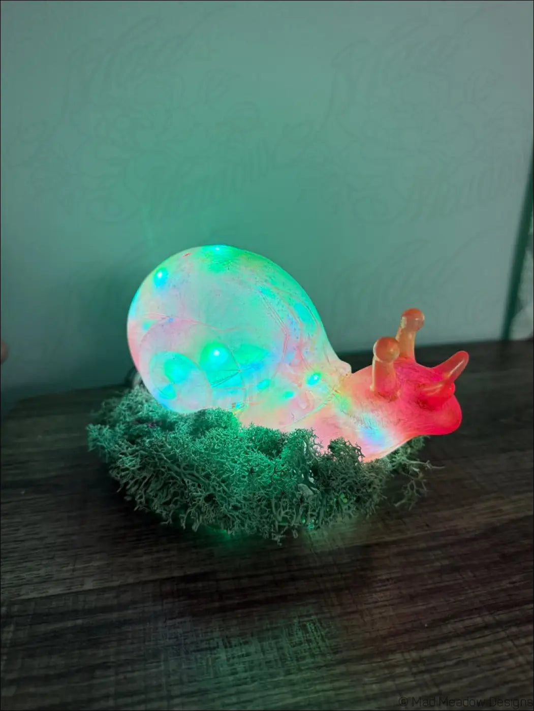 A giant pink and gold snail led lamp with glowing translucent body and colorful rgb moss light usb or battery powered