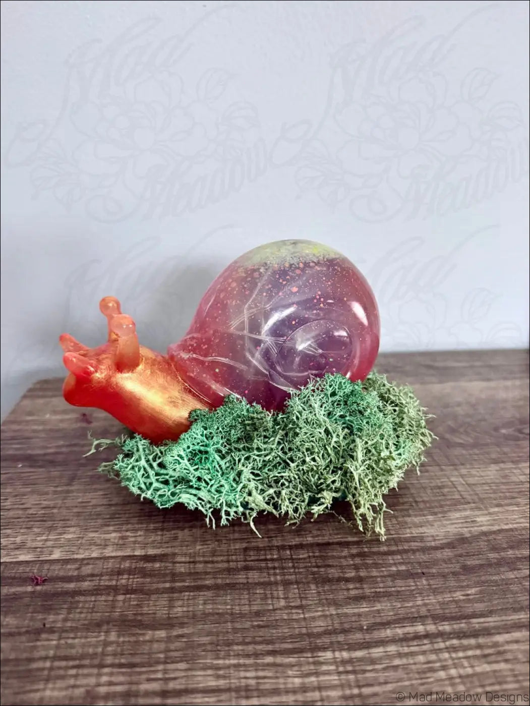 A translucent pink and purple resin giant snail figurine with a glossy finish sitting on green moss for RGB light use