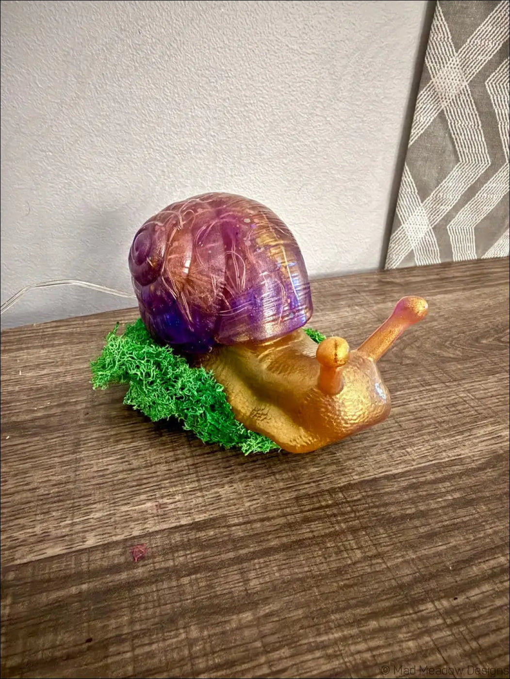 A giant translucent purple and gold snail figurine with a golden body resting on green moss usb light controlled by app