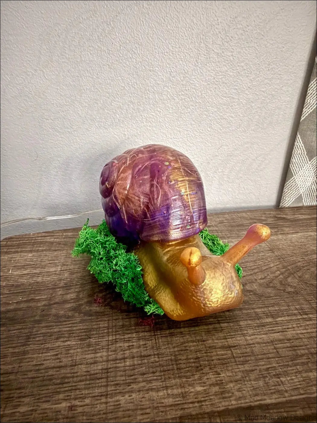 Glossy giant purple and gold snail figurine with iridescent shell and golden body resting on green moss light usb controlled