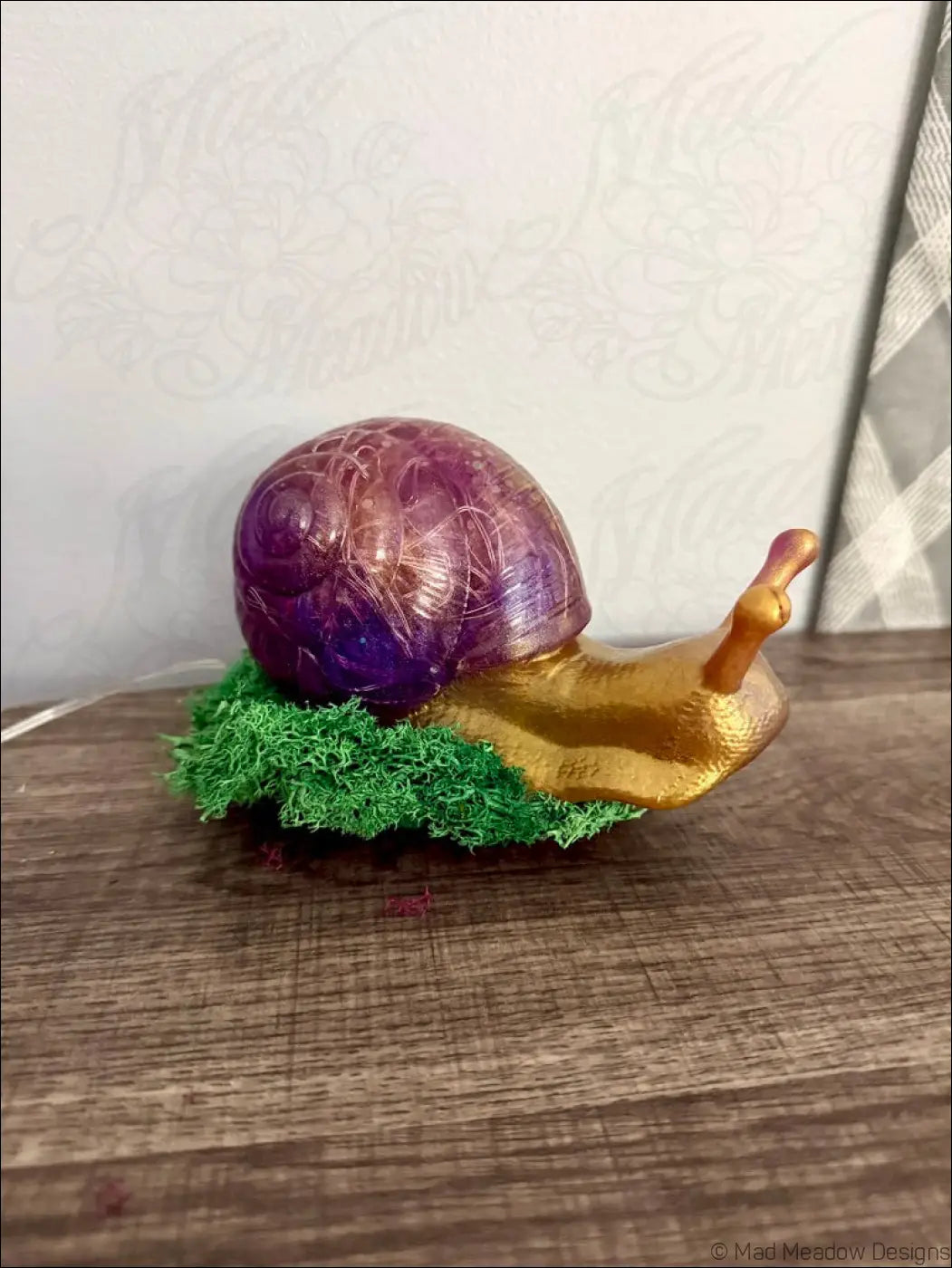 A glossy translucent purple snail figurine with a golden body on artificial moss for usb app controlled giant light