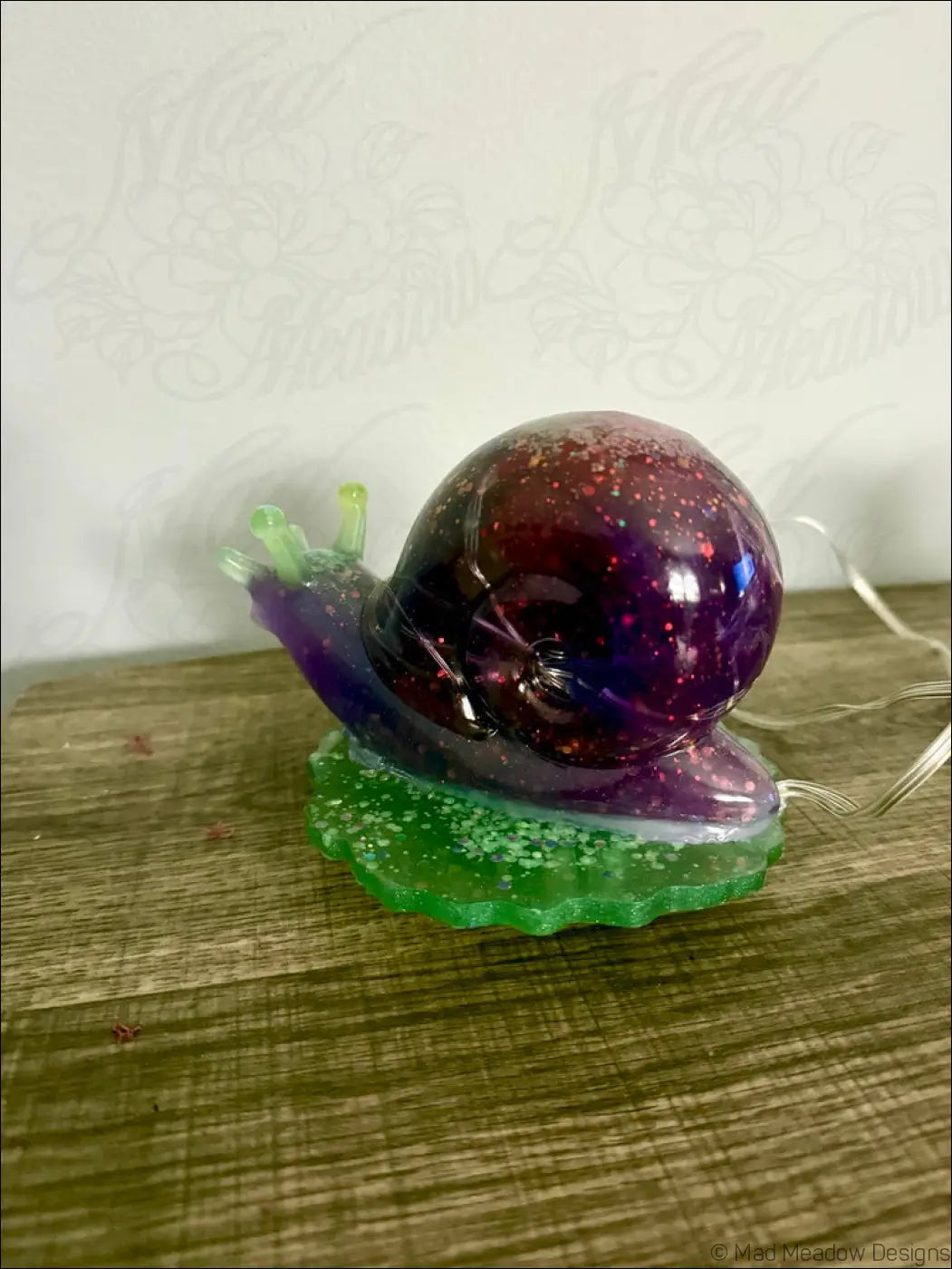 Giant purple snail light with a glossy galaxy-themed purple and red glittery shell on a green resin base usb or battery powered