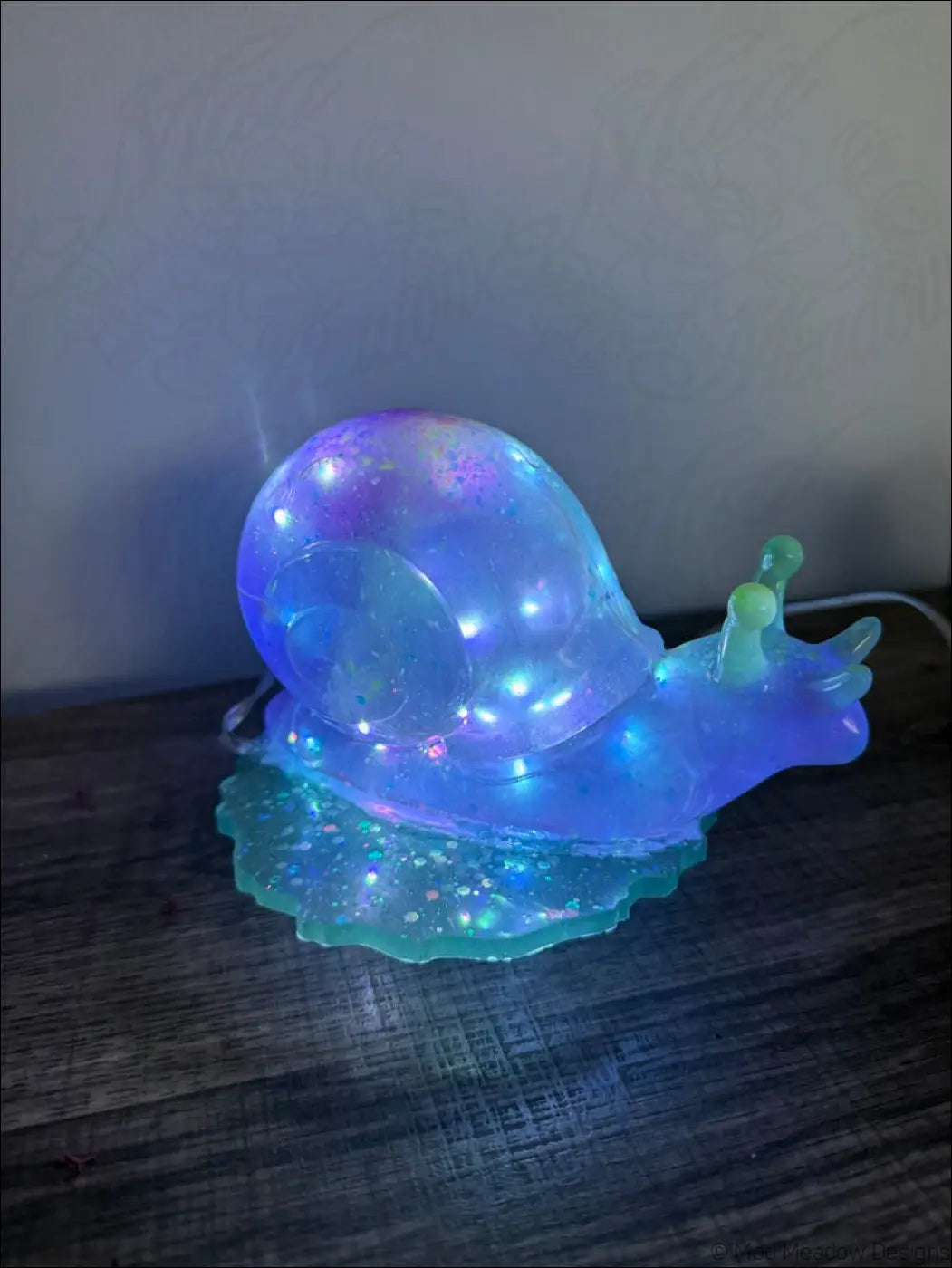 A glowing translucent blue giant purple snail light with embedded glitter and greenish shell base rgb usb battery powered