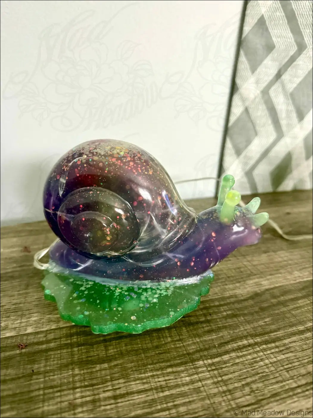A translucent purple and green giant snail light figurine with glittery details on a matching leaf base usb and battery powered