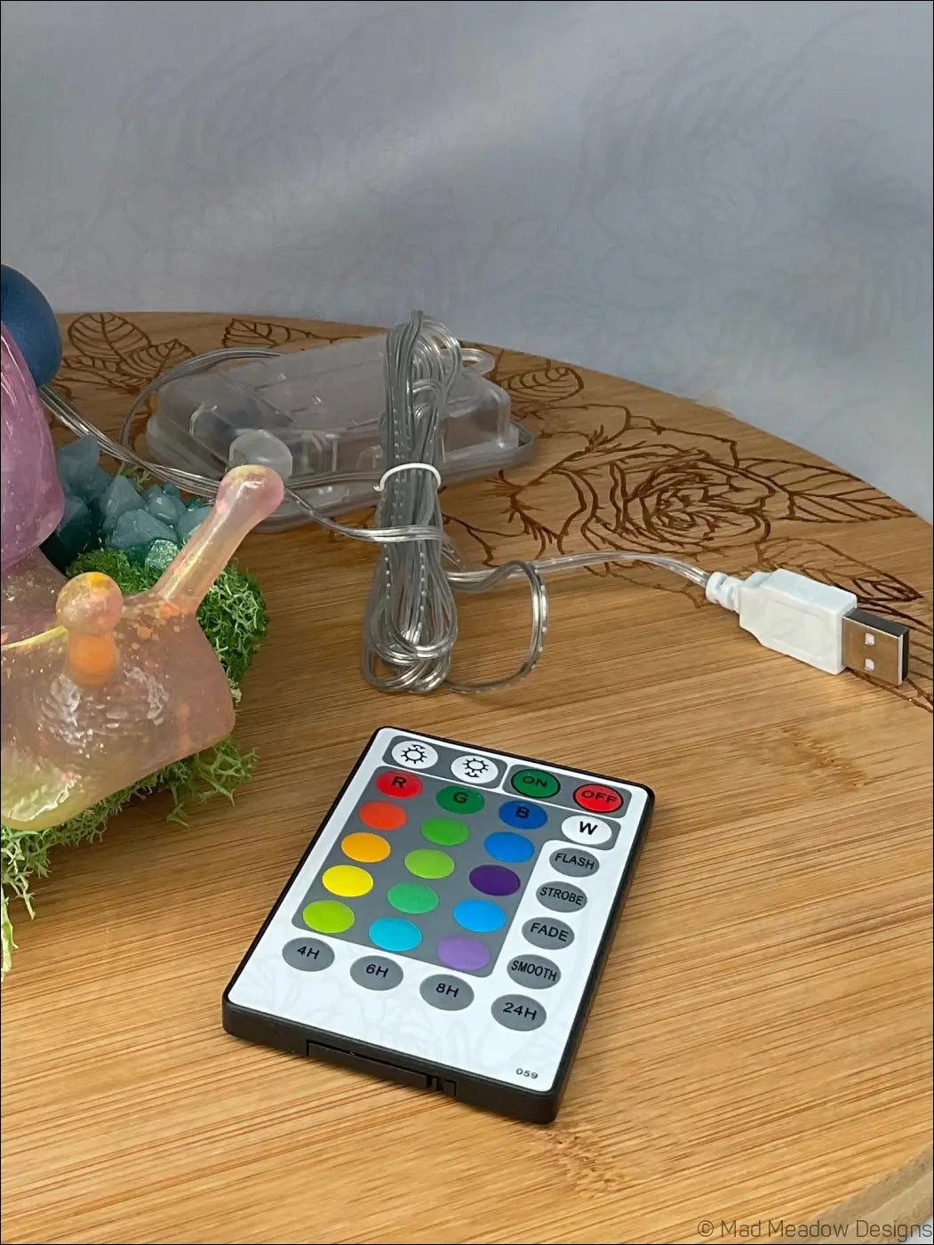 Black and white remote control with colorful buttons for the giant snail with moss and crystals rgb light