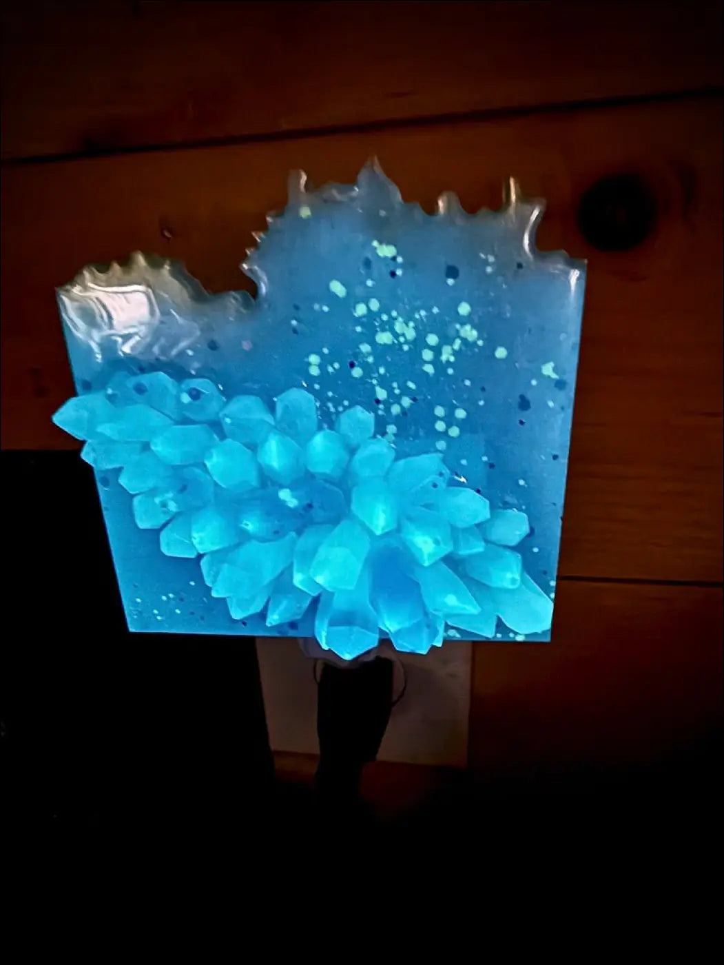 A glowing crystal cluster wall night light with blue and purple resin faceted crystals on a plug-in base