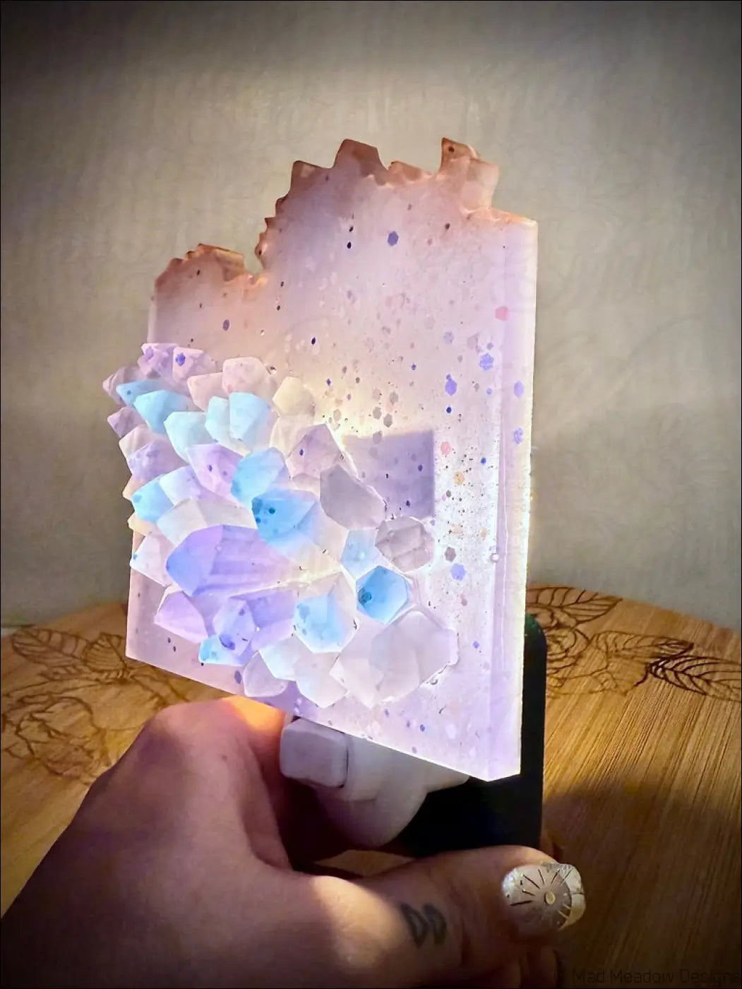 A glowing crystal cluster wall night light with lavender and blue resin and a speckled translucent base plug-in design
