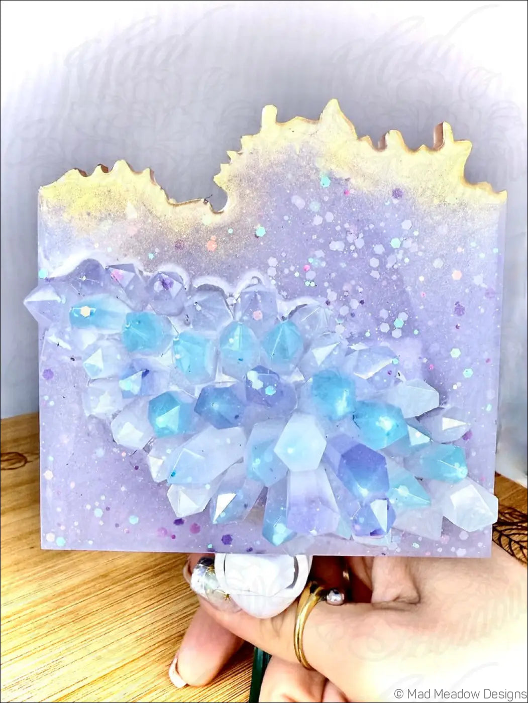 A glowing crystal cluster wall night light with lavender resin canvas and blue white translucent crystals on plug-in base