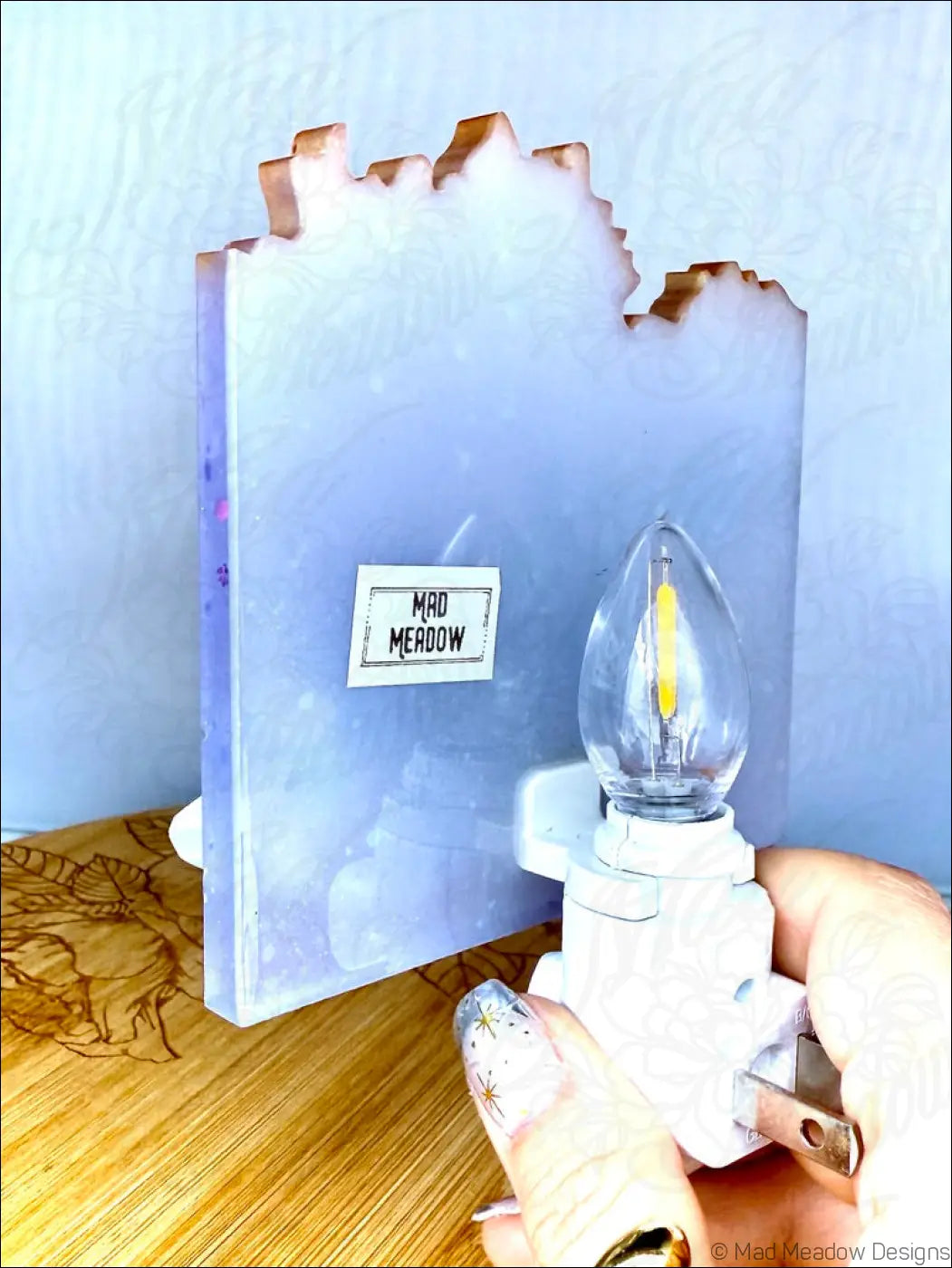 A glowing crystal cluster wall night light with a translucent lavender resin body and glittery jagged top edge